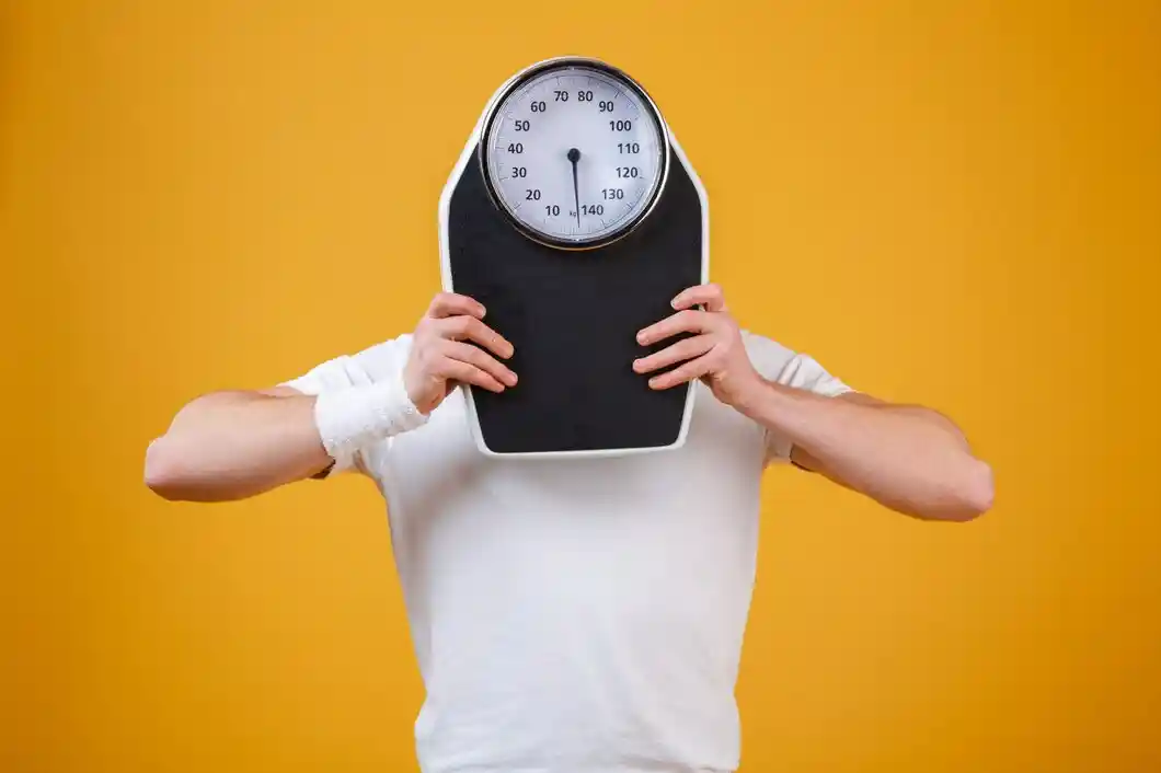 Gain weight very quickly a young main hiding his face with weight scale